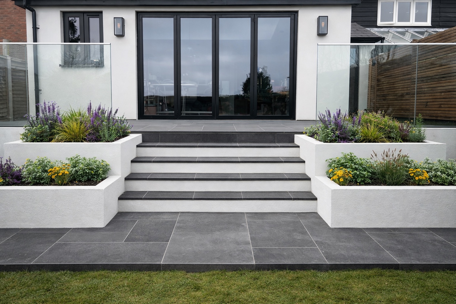 Dark-slate terrace and steps outside a modern white house with planted containers